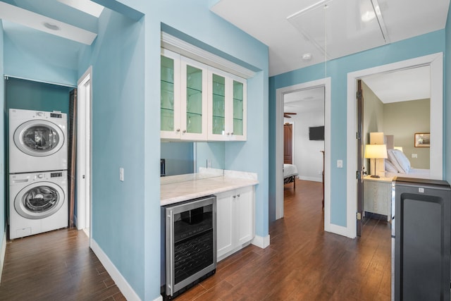 kitchen with white cabinets, wine cooler, dark hardwood / wood-style flooring, stacked washer and clothes dryer, and light stone countertops