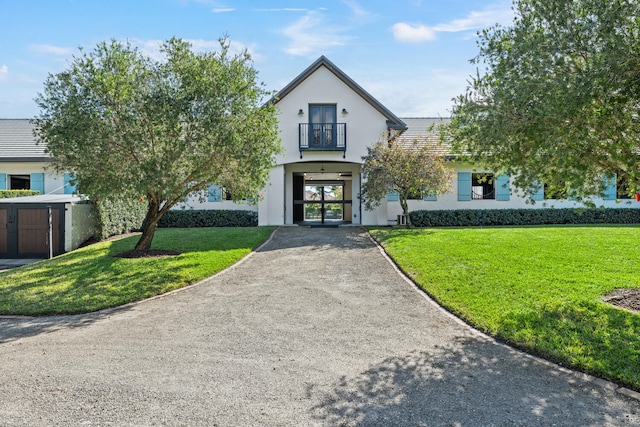 view of front of house featuring a balcony and a front lawn