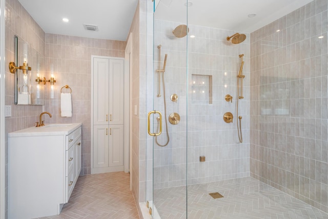 bathroom featuring vanity, a shower with door, and tile walls