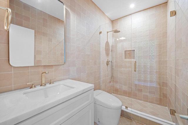 bathroom with tile walls, vanity, and a shower with door