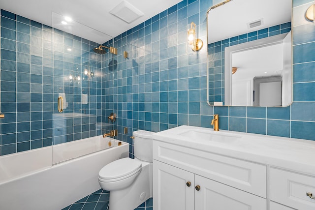 full bathroom with tile walls, tile patterned flooring, enclosed tub / shower combo, vanity, and toilet