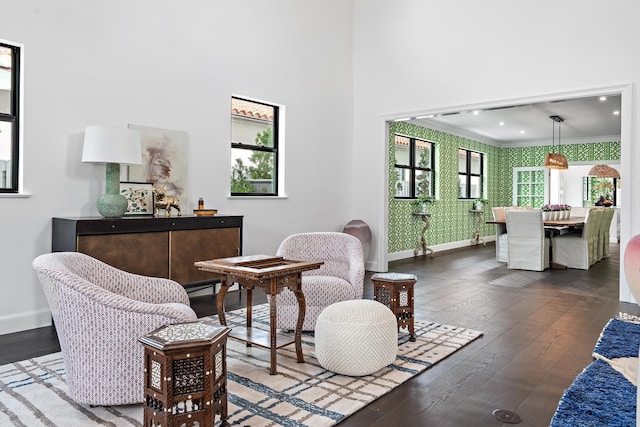 sitting room featuring hardwood / wood-style flooring, ornamental molding, and a towering ceiling