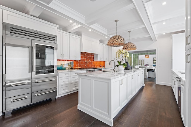 kitchen featuring hanging light fixtures, a center island with sink, white cabinets, and light stone counters