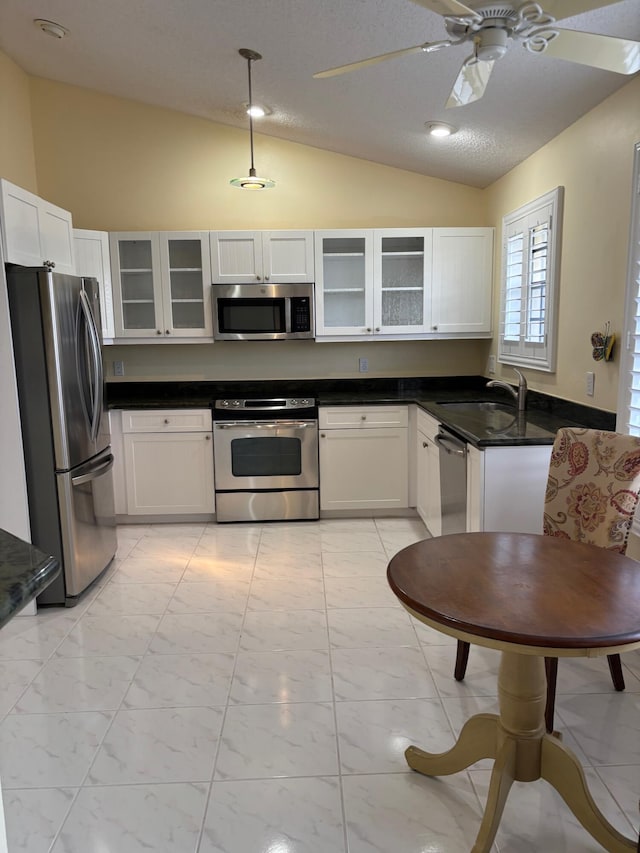 kitchen featuring stainless steel appliances, lofted ceiling, pendant lighting, white cabinets, and sink