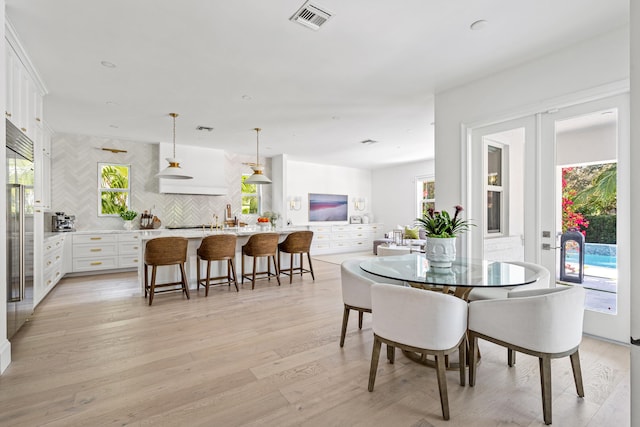 dining space featuring french doors and light wood-type flooring