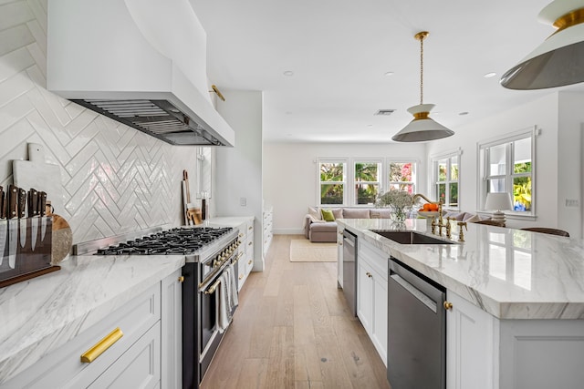 kitchen featuring sink, appliances with stainless steel finishes, white cabinets, and premium range hood