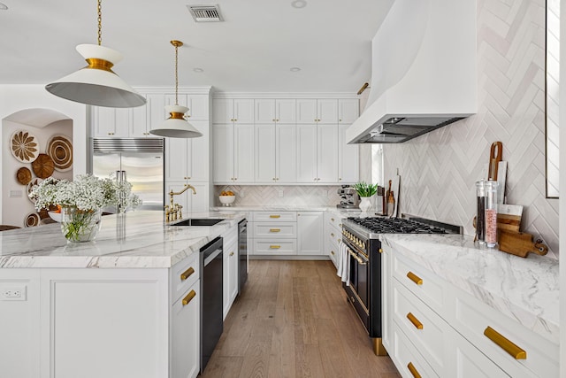 kitchen with sink, island range hood, a center island with sink, high quality appliances, and white cabinets