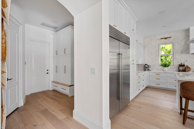 kitchen featuring built in fridge, decorative backsplash, white cabinets, and light hardwood / wood-style flooring