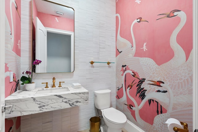 bathroom featuring tile walls, sink, and toilet