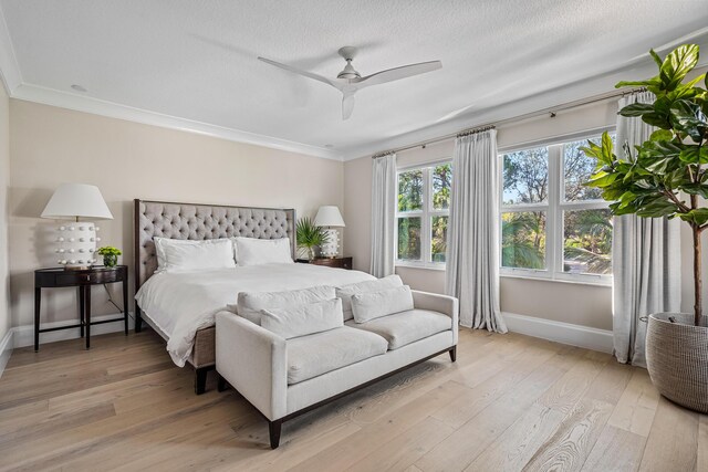 bedroom featuring ceiling fan, ornamental molding, a textured ceiling, and light hardwood / wood-style flooring