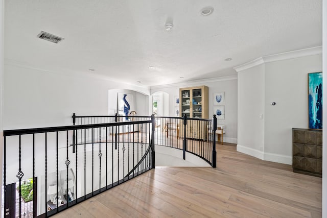 hallway featuring crown molding, plenty of natural light, a textured ceiling, and light wood-type flooring