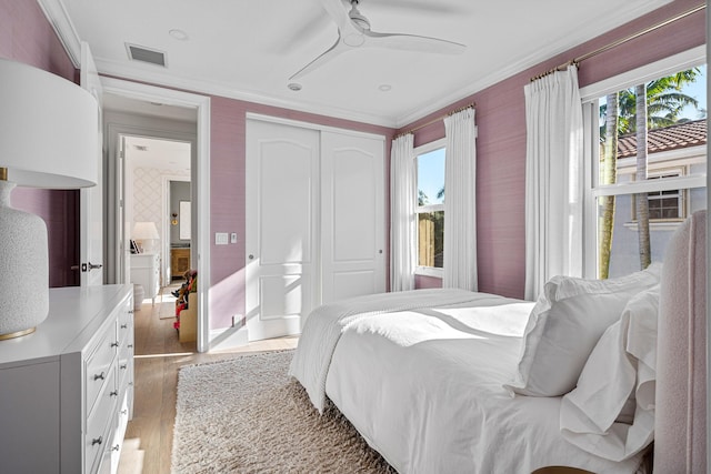 bedroom featuring multiple windows, crown molding, hardwood / wood-style floors, and a closet