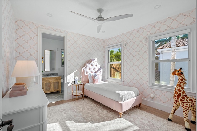 bedroom featuring connected bathroom, ceiling fan, and light wood-type flooring