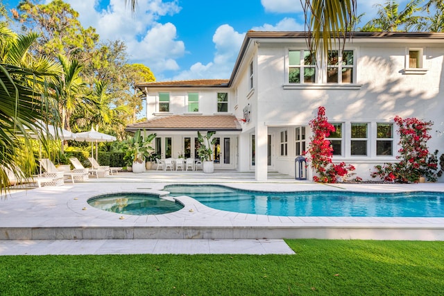 back of property featuring a pool with hot tub and a patio