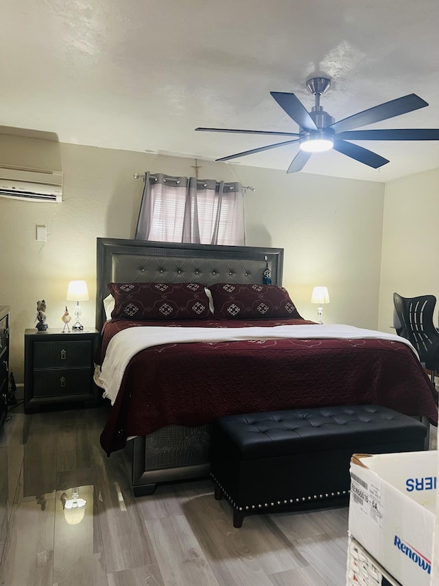 bedroom with a wall unit AC, ceiling fan, and hardwood / wood-style floors