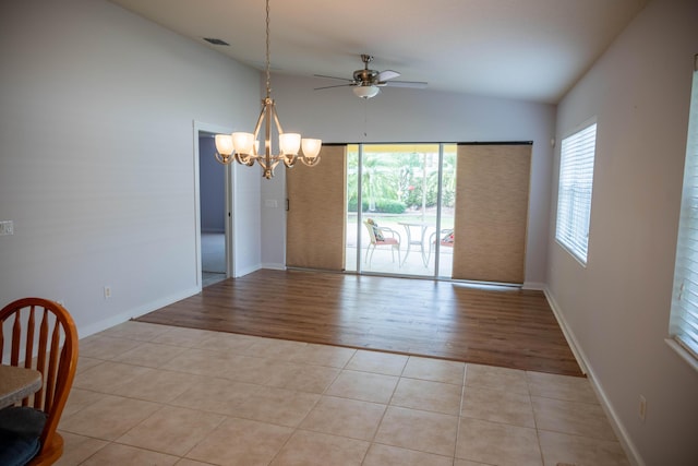 empty room with light tile patterned floors, baseboards, visible vents, lofted ceiling, and ceiling fan with notable chandelier