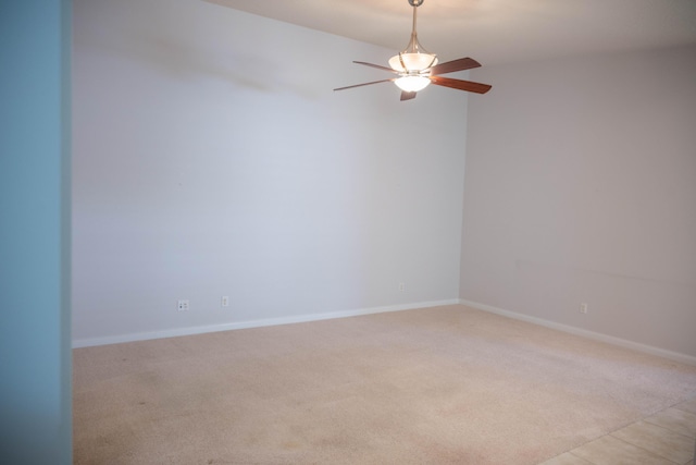 empty room with baseboards, a ceiling fan, and light colored carpet