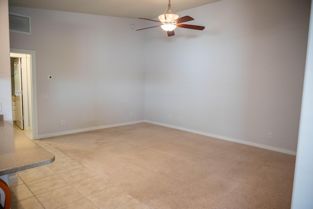 spare room with light tile patterned floors, baseboards, visible vents, light colored carpet, and ceiling fan