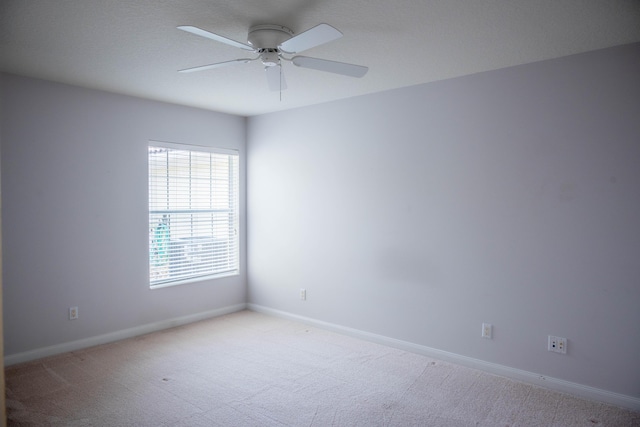 empty room with baseboards, ceiling fan, and light colored carpet