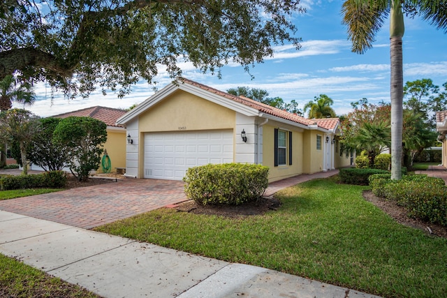 view of front of house featuring stucco siding, a tiled roof, an attached garage, decorative driveway, and a front yard