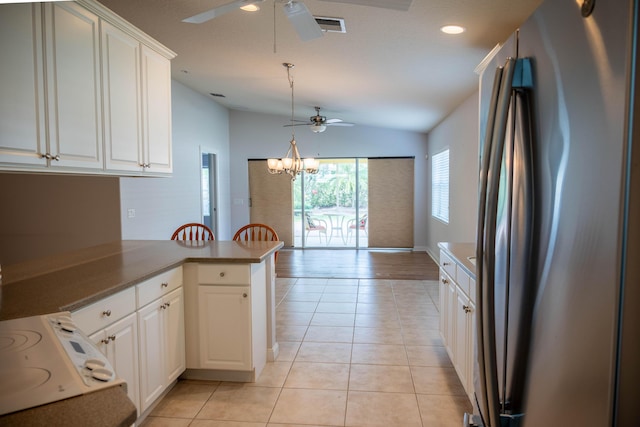 kitchen featuring light tile patterned floors, lofted ceiling, a peninsula, white cabinetry, and freestanding refrigerator