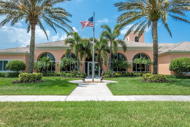 mediterranean / spanish-style home with a front yard, a tile roof, and stucco siding