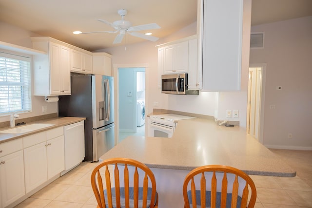 kitchen featuring stainless steel appliances, washer / clothes dryer, visible vents, light tile patterned flooring, and a sink