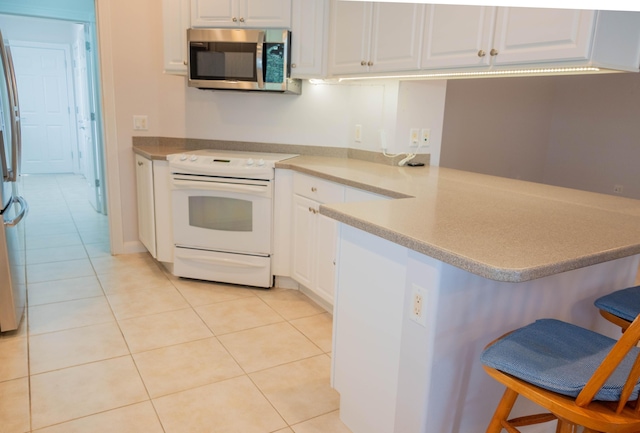 kitchen with stainless steel appliances, a peninsula, white cabinetry, and a kitchen breakfast bar