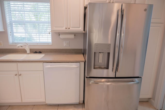 kitchen with stainless steel fridge, white dishwasher, light countertops, white cabinetry, and a sink