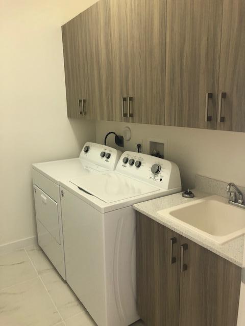 washroom featuring washer and dryer, cabinets, light tile patterned floors, and sink