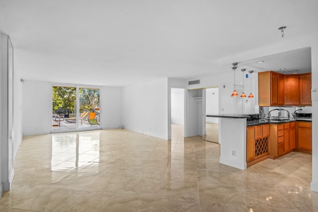 kitchen with hanging light fixtures, sink, dark stone counters, and kitchen peninsula