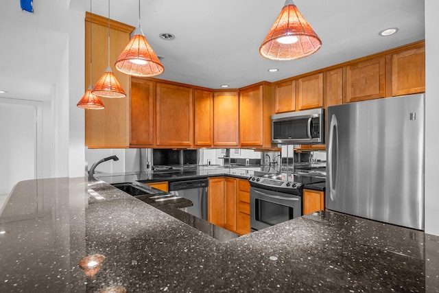 kitchen with dark stone countertops, appliances with stainless steel finishes, sink, and pendant lighting