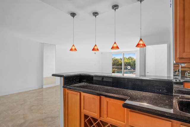 kitchen with sink, dark stone counters, and decorative light fixtures