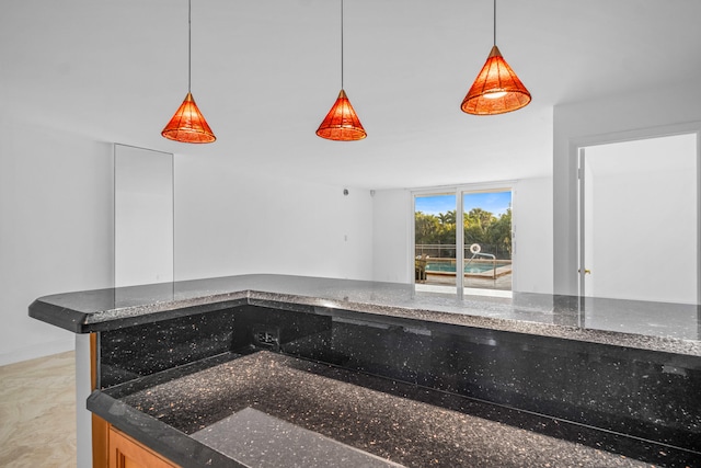 kitchen featuring hanging light fixtures and dark stone counters