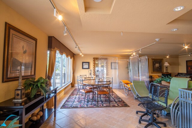 dining area with tile patterned floors, rail lighting, and a textured ceiling