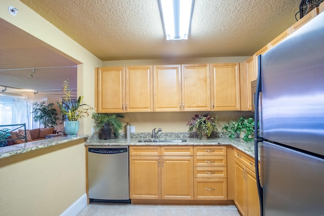 kitchen featuring light tile patterned flooring, light brown cabinetry, sink, light stone counters, and stainless steel appliances