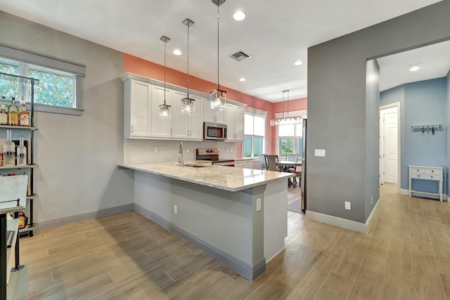 kitchen with pendant lighting, kitchen peninsula, light stone countertops, appliances with stainless steel finishes, and white cabinets