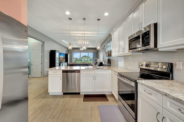 kitchen featuring decorative light fixtures, white cabinets, appliances with stainless steel finishes, and kitchen peninsula