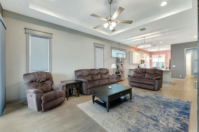 living room with ceiling fan and a tray ceiling