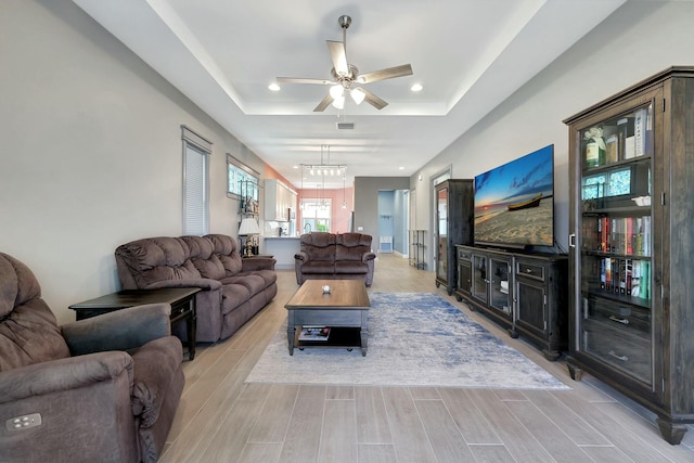 living room featuring ceiling fan and a tray ceiling