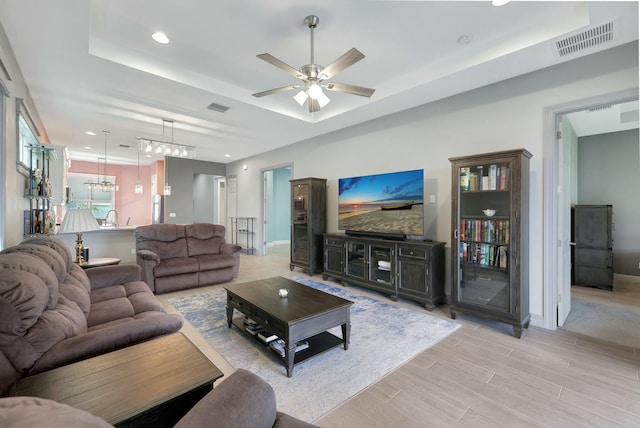 living room with ceiling fan, sink, and a tray ceiling