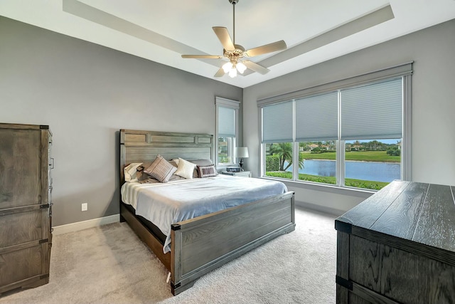 bedroom featuring ceiling fan, light colored carpet, and a water view