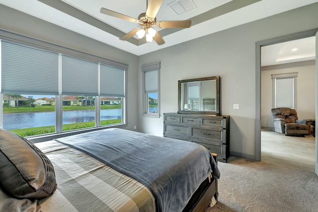 bedroom featuring a water view, light colored carpet, and ceiling fan