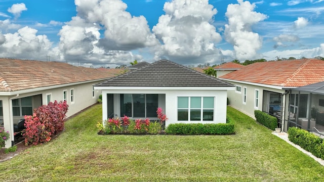 back of property with glass enclosure and a lawn