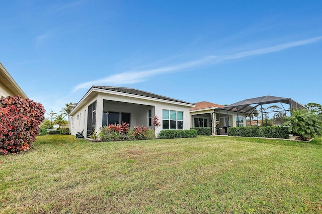 back of property with glass enclosure and a yard