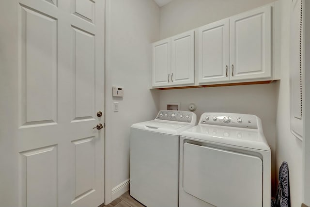 laundry area featuring cabinets, washer and dryer, and light hardwood / wood-style flooring