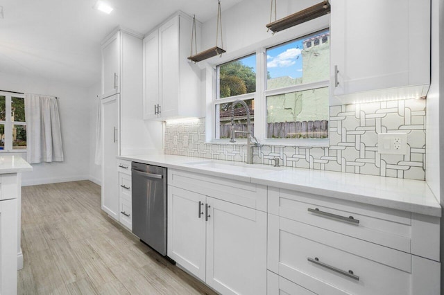 kitchen featuring tasteful backsplash, dishwasher, light stone counters, and white cabinetry