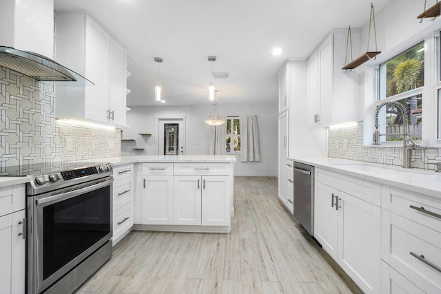 kitchen with white cabinetry, wall chimney range hood, stainless steel appliances, sink, and backsplash