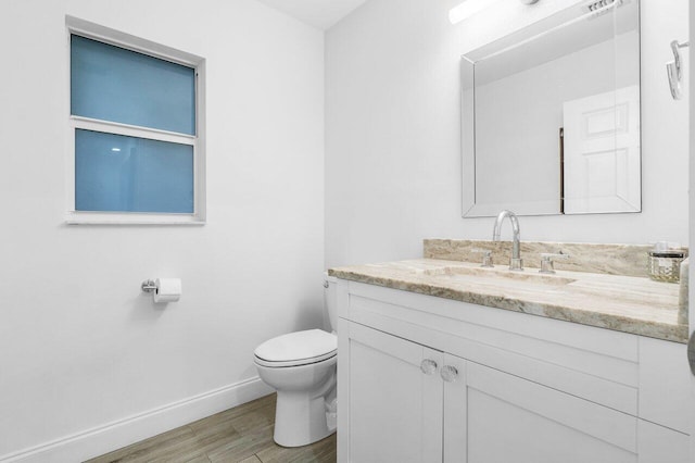 bathroom with toilet, vanity, and hardwood / wood-style flooring