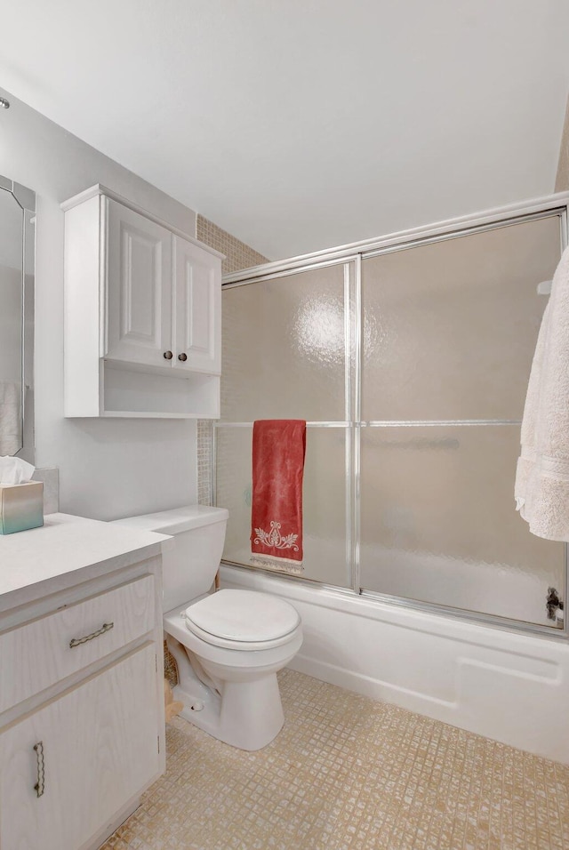 full bathroom with combined bath / shower with glass door, vanity, and toilet